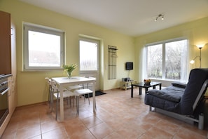 A kitchen with a dining table and chairs, a sofa, and a TV.