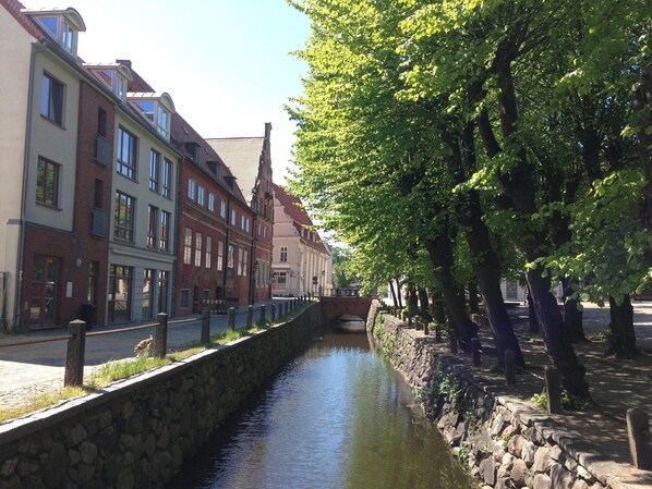 Un canal bordé de murs en pierre et d’une rangée de bâtiments à l’architecture traditionnelle.