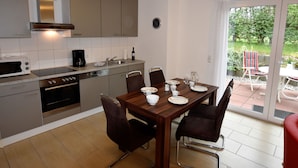 A modern kitchen with a dining area, a coffee maker, and a clock on the wall. - Modernes Ferienhaus in Boiensdorf am Meer (Boiensdorf)