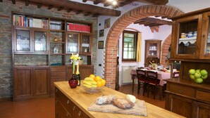 A rustic kitchen with wooden cabinets, a stone wall, and a brick archway. - Belvilla by OYO Villa Sara (Lucignano)