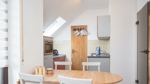 Eine kompakte Küche mit Essbereich, ausgestattet mit einem Holztisch und Stühlen, einer Mikrowelle und einer Kaffeemaschine.