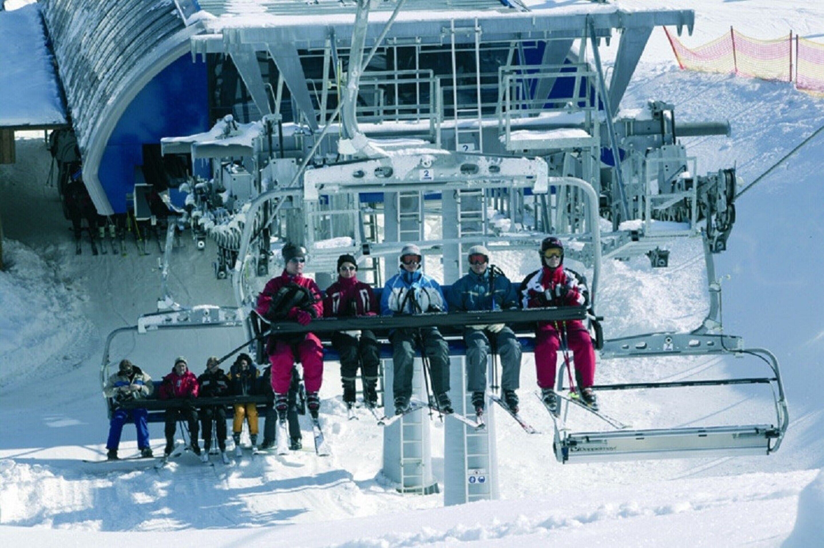 A ski lift with passengers seated on it.