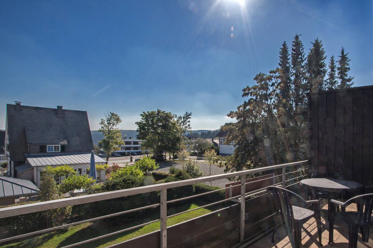 A balcony with a view of a residential area, including houses and trees.