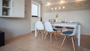 A modern dining area with a stone accent wall, pendant lighting, and a white table with four chairs. - Large Apartment near Ski Area in Winterberg Germany (Winterberg)