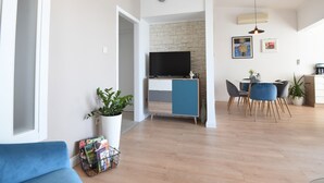 A modern living room with a sofa, a coffee table, and a TV on a stand. There is a dining area with a table and chairs. - Scenic Apartment in Maslenica With Terrace (Jasenice)