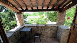 A covered patio with stone walls, a table, and two chairs. - Elysian Escape - A Paradise (San Venanzo)