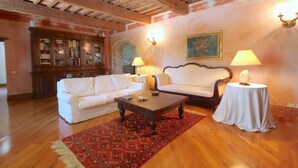 A living room with a wooden ceiling, a white sofa, a coffee table, and a red patterned rug. - Elysian Escape - A Paradise (San Venanzo)