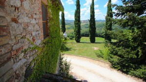 A rustic stone building with ivy, a gravel path, and a view of distant trees and hills. - Elysian Escape - A Paradise (San Venanzo)