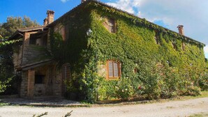 A historic stone building with ivy-covered walls and a traditional stone roof. - Elysian Escape - A Paradise (San Venanzo)