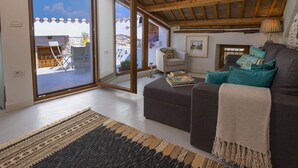 A modern living room with a sofa, a coffee table, and a fireplace. There is a large sliding glass door leading to an outdoor area with a chair and a table. - Holiday Home in Vodnjan Near the Sea (Vodnjan)
