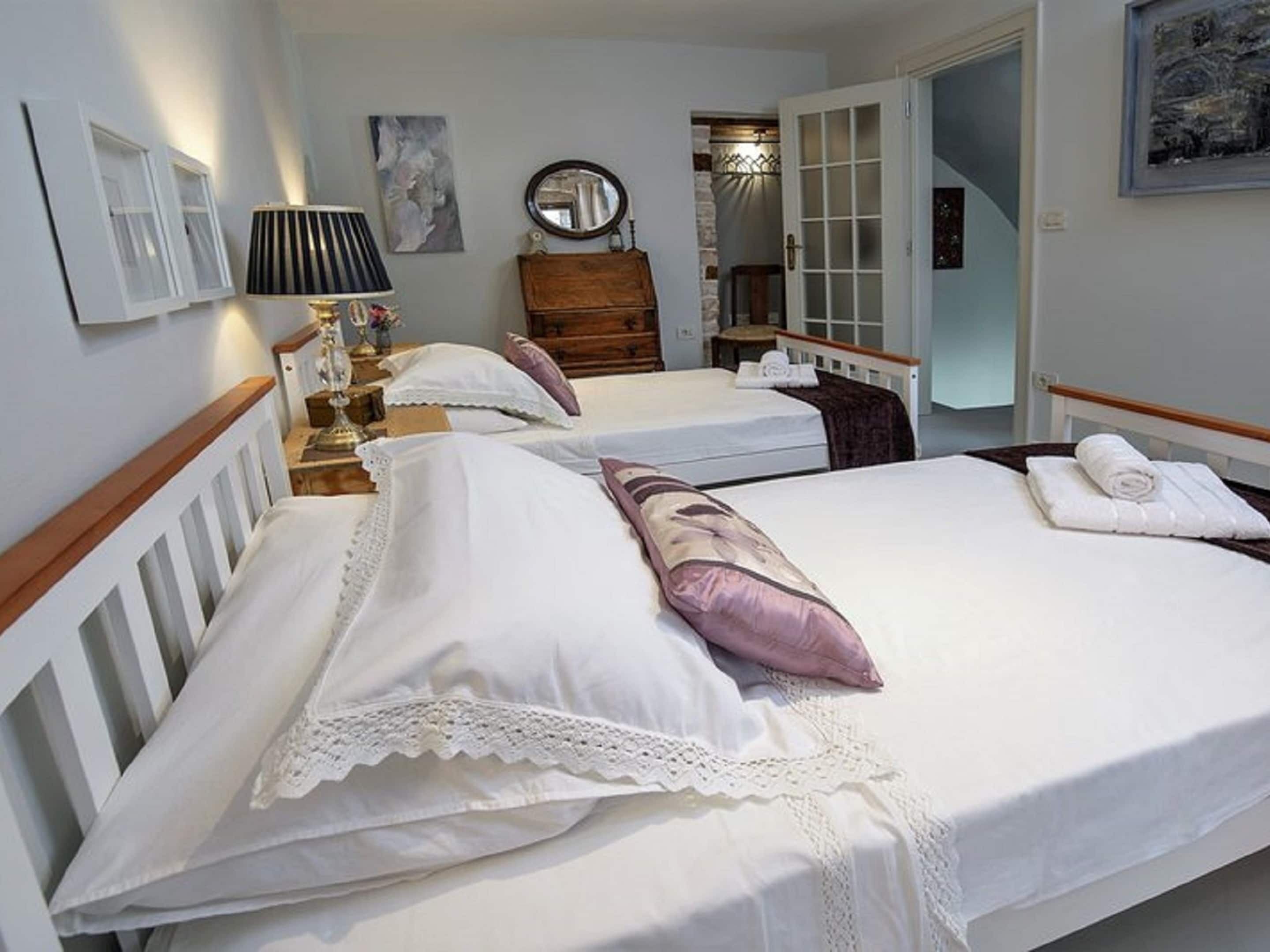 A hotel room with two beds, a wooden dresser, a mirror, and a lamp.