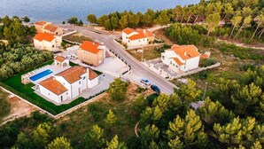 An aerial view of a coastal residential area with houses, a swimming pool, and a road. - Villa With Private Pool and Garden (Novigrad)