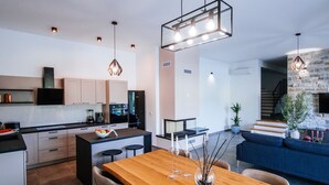 A modern kitchen with a central island, wooden dining table, and pendant lighting. - Villa With Private Pool and Garden (Novigrad)