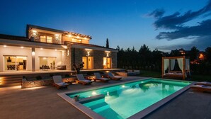 A modern house with a swimming pool, outdoor seating, and a well-lit entrance. - Villa With Private Pool and Garden (Novigrad)