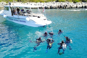Un bote blanco con la inscripción "TREASURE DIVING CENTER", llevando buzos en el agua.