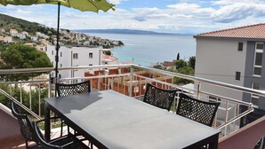 Ein Balkon mit Tisch und Stühlen mit Blick auf eine Küstenstadt und das Meer.