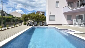 Ein Pool mit Liegestühlen und einem Gebäude mit Balkonen.