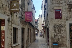 Una calle estrecha flanqueada por edificios, con letreros de una joyería, un hotel y un restaurante.
