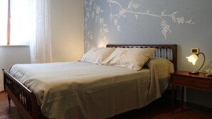 Un dormitorio con cama, mesita de noche, lámpara y un papel tapiz con estampado floral.