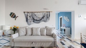 Un salon avec un canapé, un tapis à motifs et une décoration murale.