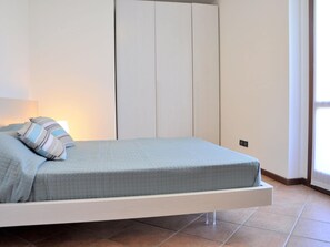 A bed with a quilted mattress, pillows, and a bedside table.