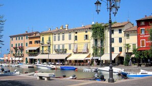 A waterfront area with boats docked, buildings with balconies, and a street lamp. - Holiday Home in Lazise Near Lake Garda (Lazise)