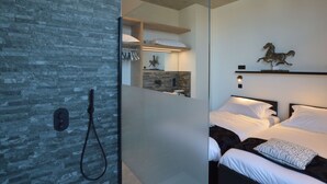 A modern bedroom with a large bed, a shower, and a stone wall. - Modern Dalhem Villa With Views (Dalhem)