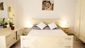 A bedroom with a bed, bedside tables, a dresser, a mirror, and a wall-mounted artwork. - Apartment in Dar?owo With Garden (Darlowo)
