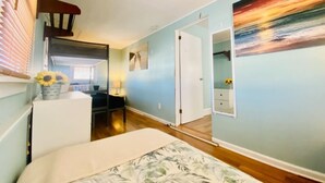 Un dormitorio con una cama, una mesita de noche, una lámpara y un cuadro en la pared.
