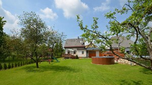 A residential backyard with a well-maintained lawn, a wooden playset, and a circular wooden structure. - Holiday Home With Private Pool in Bohemian (Vrchlabi)