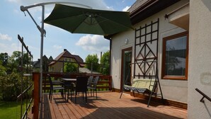 A wooden deck with outdoor furniture, a swing, and a green umbrella. - Holiday Home With Private Pool in Bohemian (Vrchlabi)