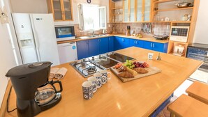 Une cuisine moderne avec des meubles bleus, une cuisinière à gaz, une machine à café et un assortiment de produits pour le petit-déjeuner disposés sur le comptoir.