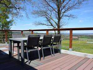 Eine Terrasse im Freien mit Tisch und Stühlen mit Blick auf eine schöne Landschaft.