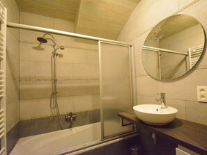 A bathroom with a glass-enclosed shower, a white sink, and a round mirror on the wall. - Charming Chalet in Vielsalm (Vielsalm)