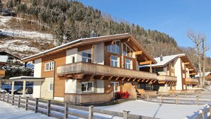 A wooden chalet with a balcony, a covered outdoor seating area, and a view of a snowy hillside. - Majestic Apartment in Zell am See near Ski Area (Zell am See)