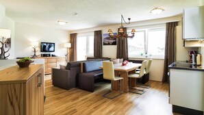 A modern hotel room with a dining area, sofa, and kitchen. - Majestic Apartment in Zell am See near Ski Area (Zell am See)
