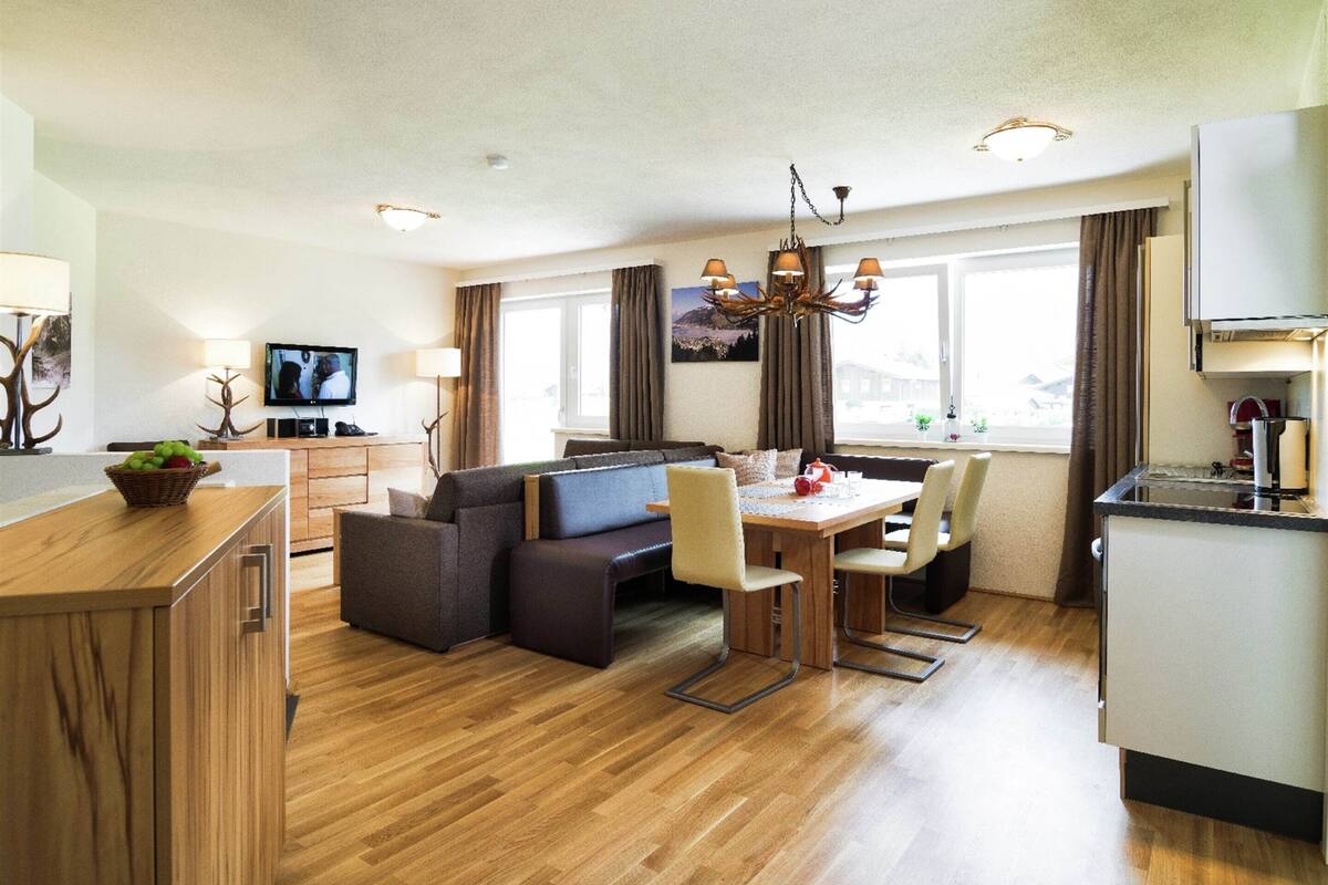 A modern hotel room with a dining area, sofa, and kitchen.