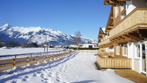 A snow-covered path leading to a wooden building with a balcony, set against a backdrop of snow-capped mountains. - Majestic Apartment in Zell am See near Ski Area (Zell am See)