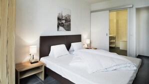 A hotel room with a large bed, bedside tables with lamps, a framed picture on the wall, and a sliding door leading to a bathroom. - Majestic Apartment in Zell am See near Ski Area (Zell am See)