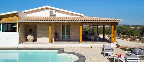 A house with a swimming pool, outdoor furniture, and a covered patio area.