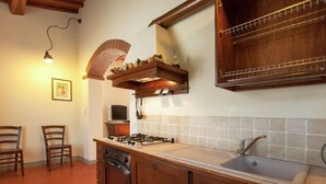A kitchen with wooden cabinets, a gas stove, a sink, and a tiled backsplash. - Villa with Spacious Garden, Swimming Pool, Hot Tub, Tennis Court near Cortona (Cortona)