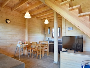 Cozy cabin interior with a dining area, television, and clock.