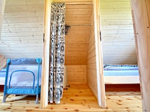 A small, enclosed wooden cabin with a bunk bed and a mosquito net.