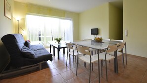 Een eetgedeelte met een tafel, stoelen, een bank en een televisie.