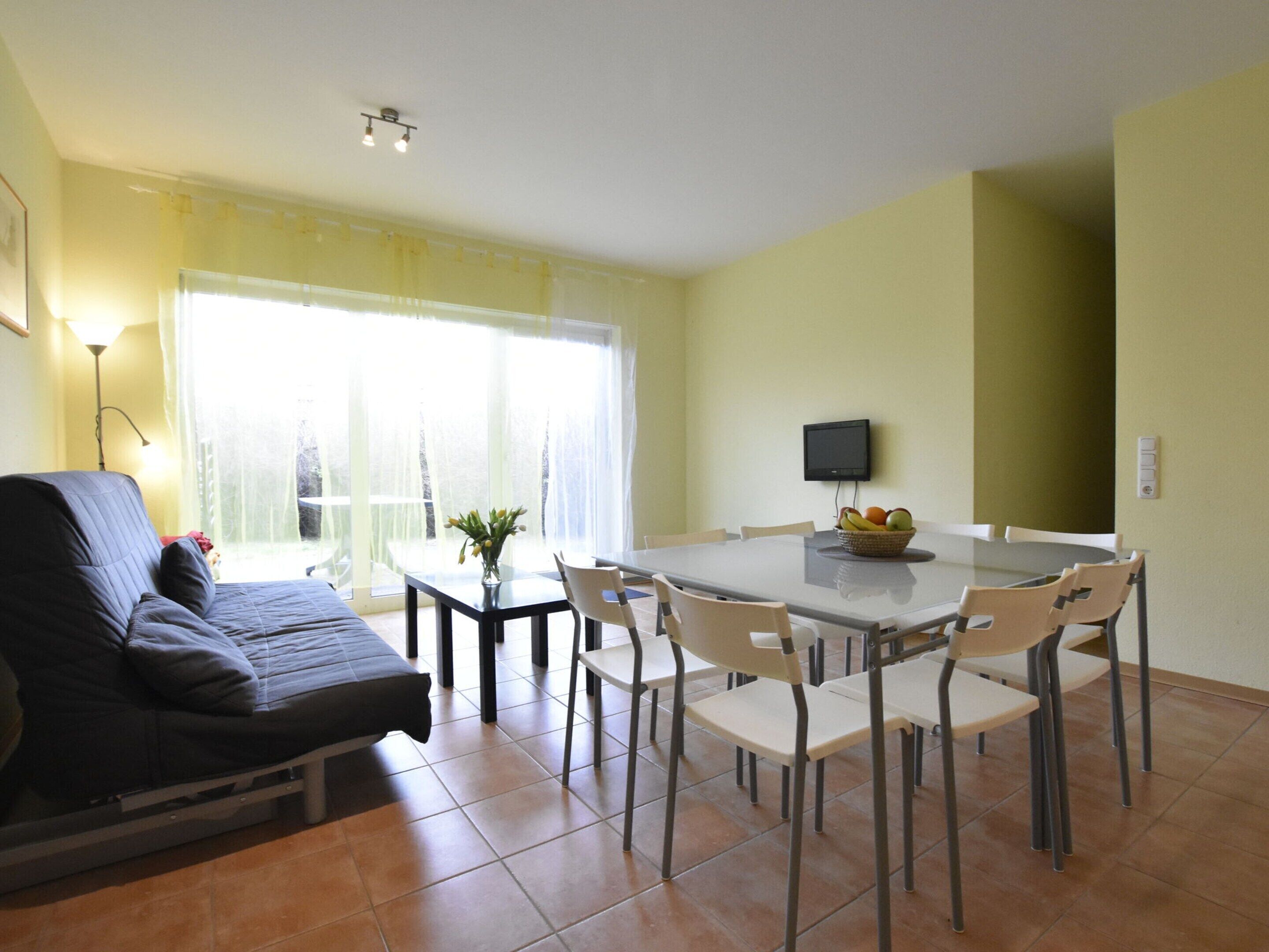 A dining area with a table, chairs, a television, and a sofa.
