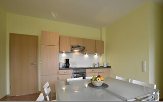 Una cocina moderna con armarios de madera, una estufa de acero inoxidable y una mesa de comedor con un frutero.