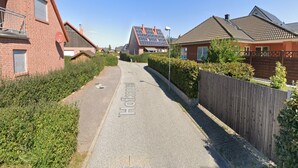 Een woonstraat met huizen, een heldere lucht en zonnepanelen op een dak.