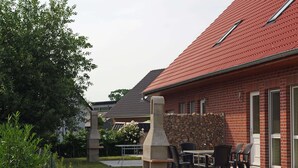 Een gebouw van baksteen met een rood dak, een terras en een stenen constructie.