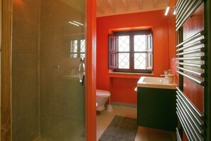 A bathroom with a toilet, a sink, a window, and a shower area.