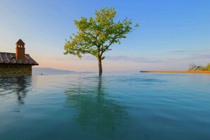 A tree in water with a stone building and a clear sky.